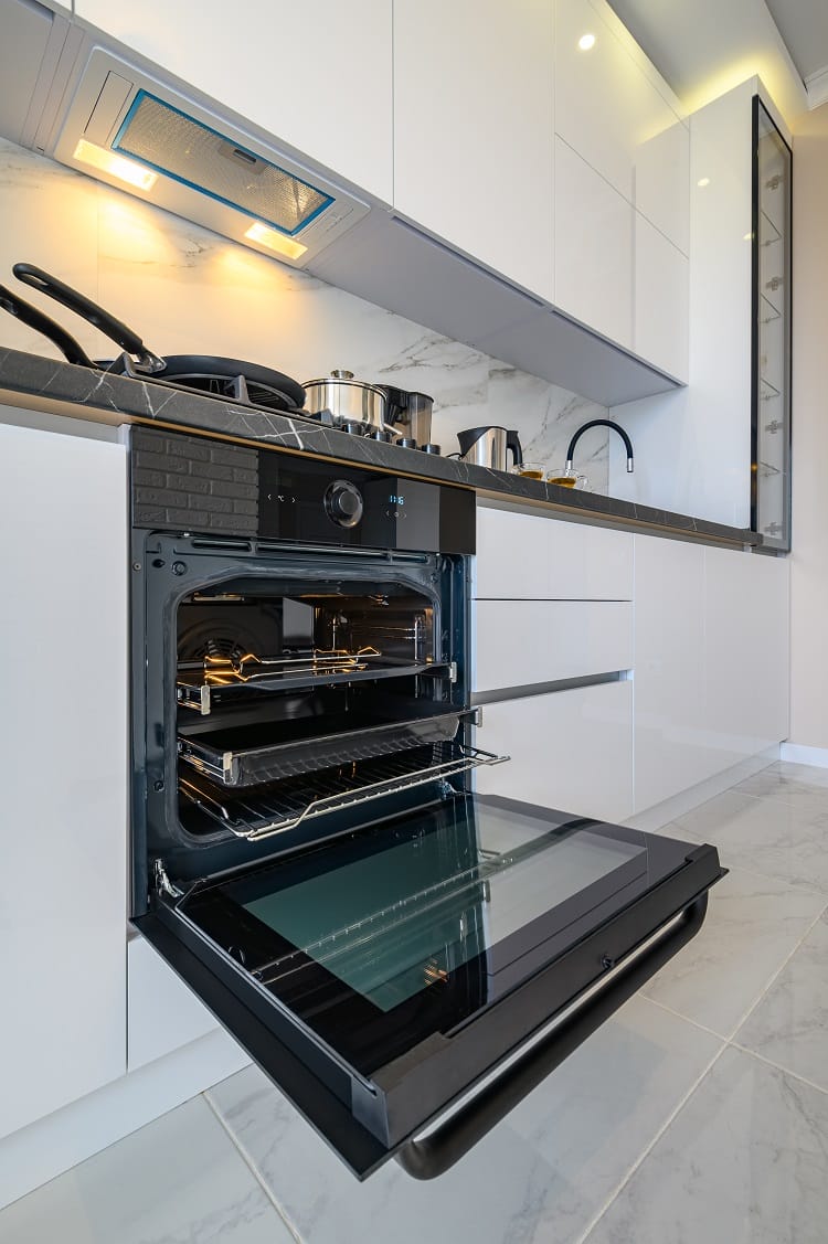 an oven door open in a white kitchen an oven door open in a white kitchen