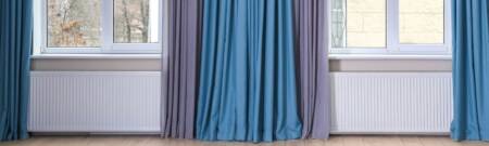 two radiators under windows with blue curtains hanging over
