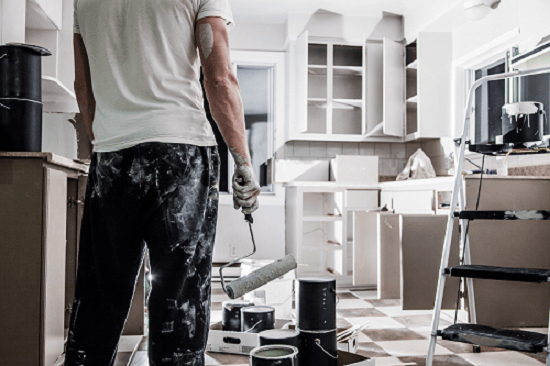big-painting-job a man standing in his kitchen with a paint roller in his hand