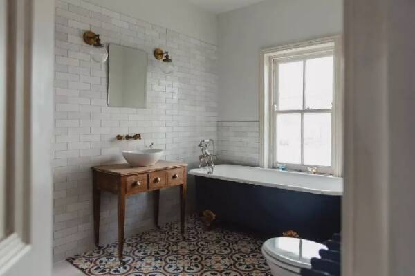 edwardian 2 A blue freestanding bath in a white bathroom under a window.