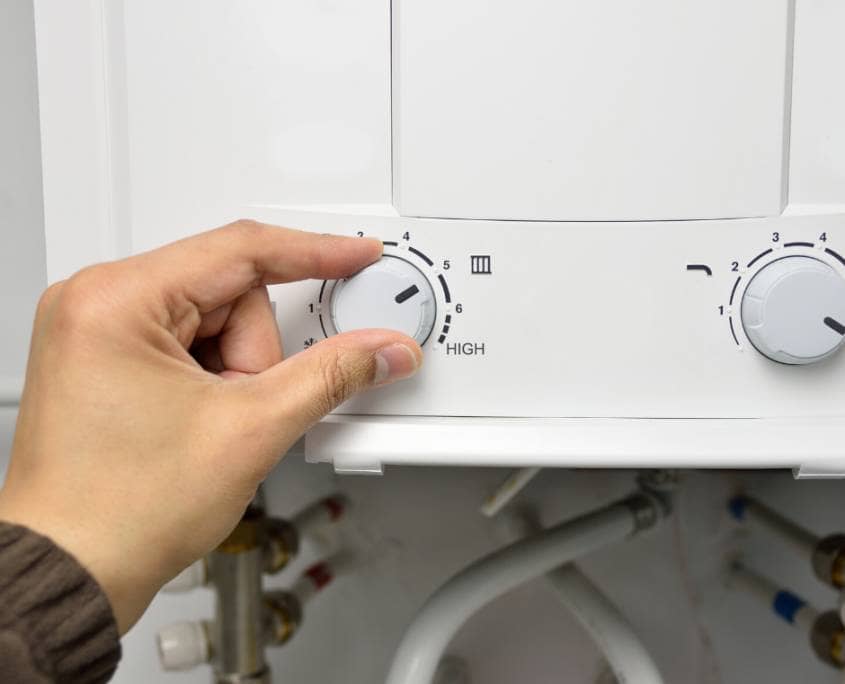White boiler system with dials Close up of left hand adjusting left dial on white boiler system