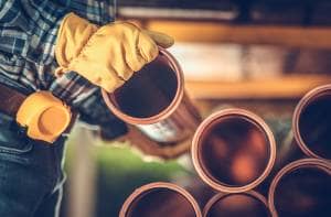 Plastic heating pipes stacked up Heating professional with yellow gloves placing plastic heating pipes on top of one another