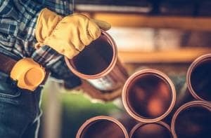 Heating professional with yellow gloves placing plastic heating pipes on top of one another