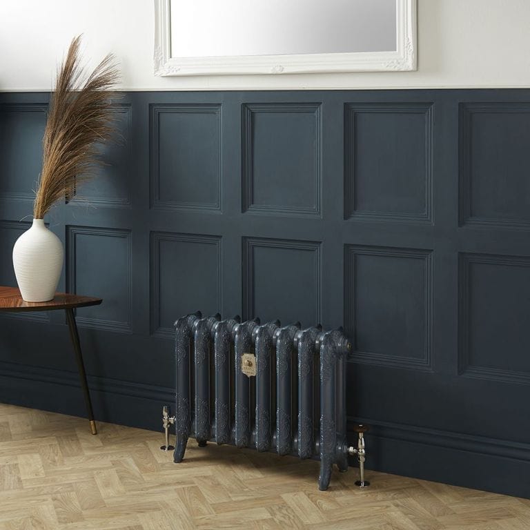 Milano Beatrix Farrow & Ball hague blue 2 column cast iron radiator in front of blue wall nearby small table with vase