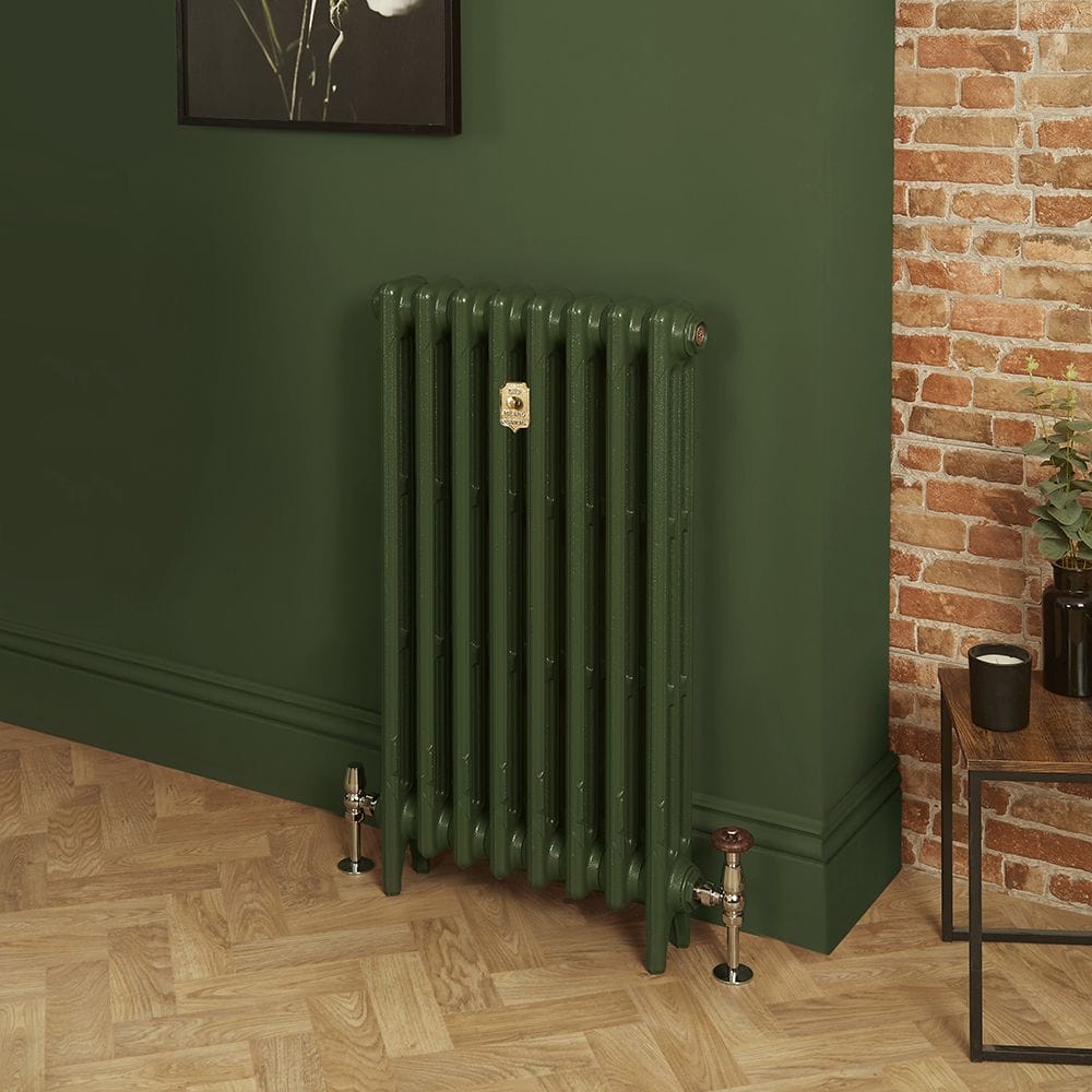 Milano Mercury duck green cast iron radiator on wooden floor and green background near small table with candle