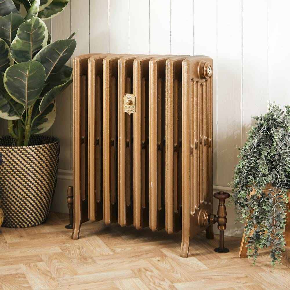 Milano Isabel burnt gold cast iron radiator on wooden floor next to houseplants