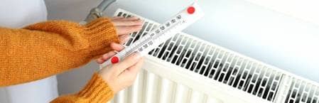 woman checking radiator efficiency with thermometer