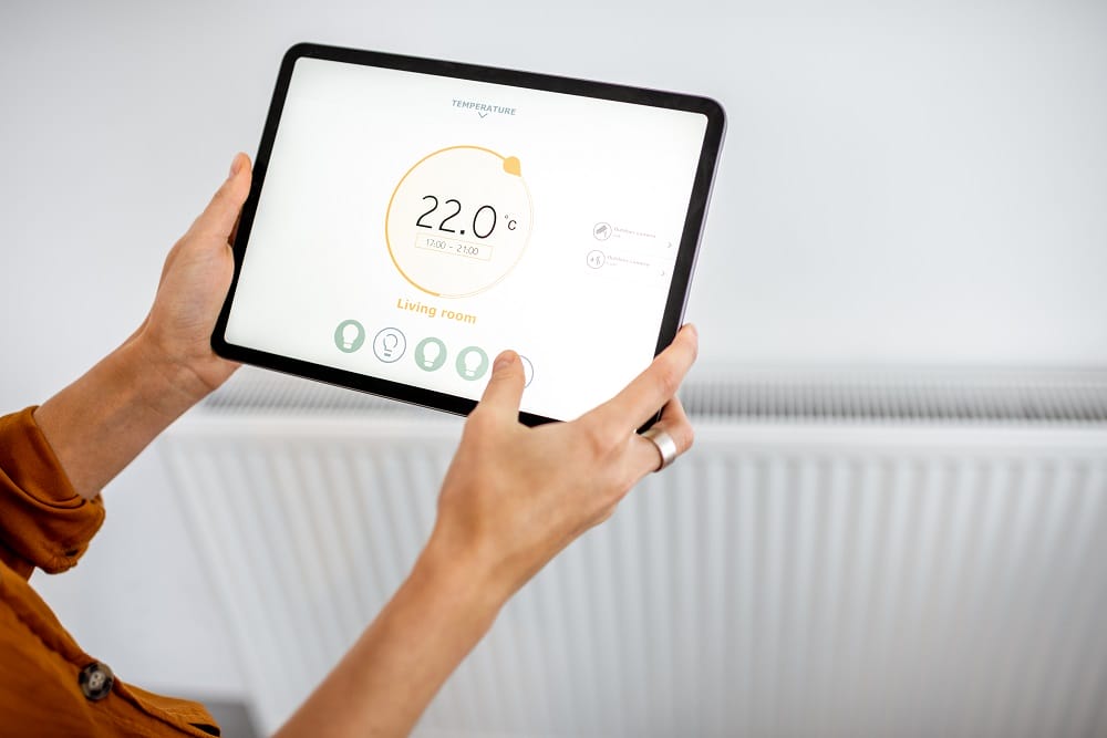 Hand controlling smart heating on a smart tablet with white radiator in background