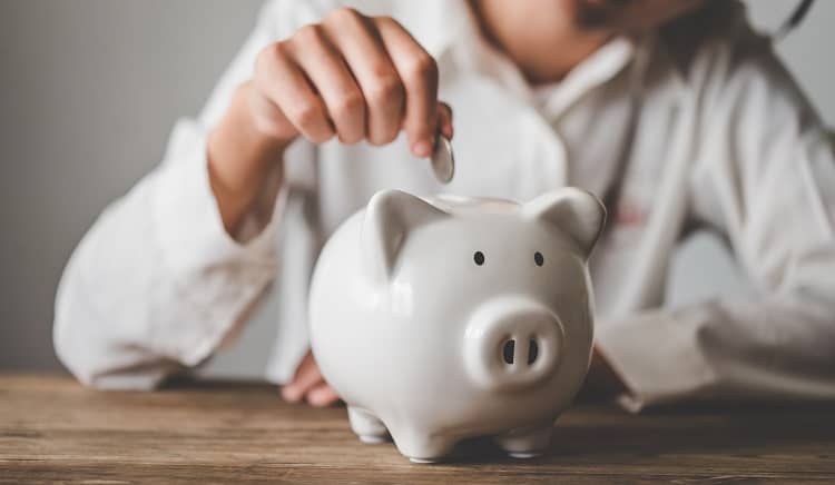 A woman putting money in her piggy bank after saving money on heating
