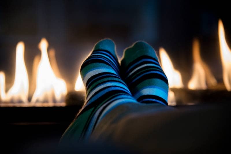 Feet in stripy socks up in front of fireplace