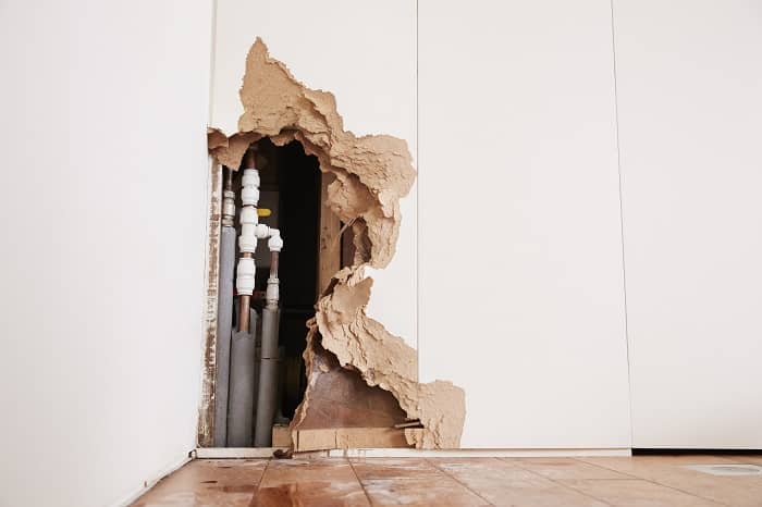 a broken wall showing exposed pipework
