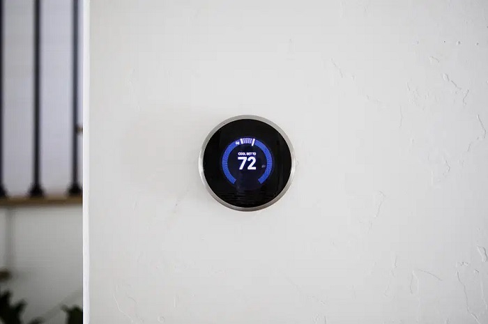 A modern touch screen thermostat on the wall of a home