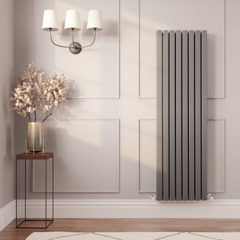 Milano Capri anthracite flat panel vertical designer radiator on light wall nearby small table with vase and fake plant beneath triple light fitting