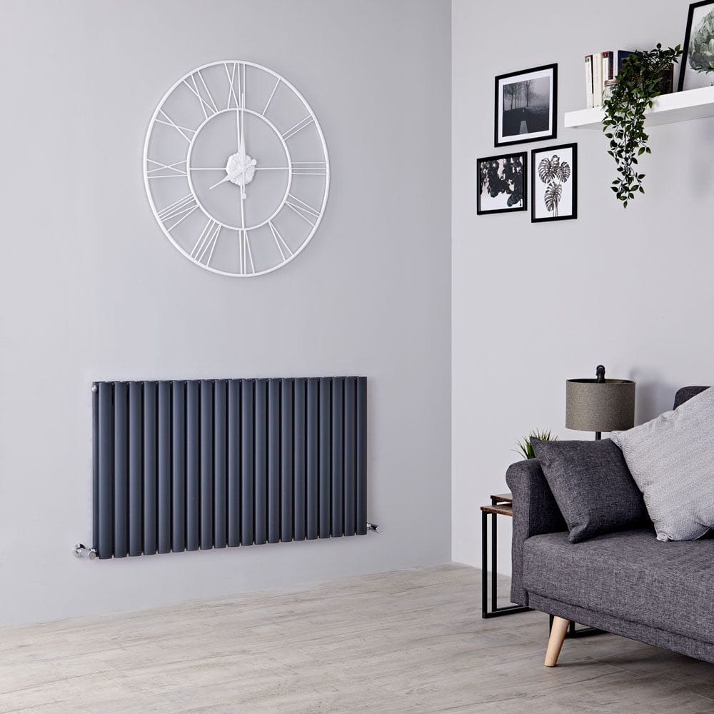 Milano Aruba anthracite horizontal designer double radiator on white wall beneath large clock adjacent to grey settee in front of wall with artwork