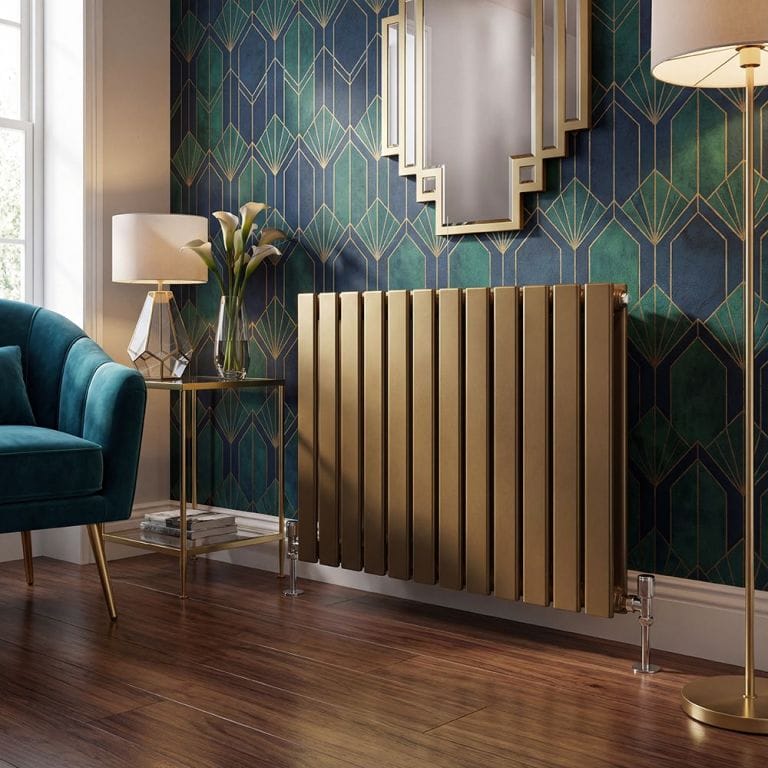 Milano Alpha metallic flat panel horizontal designer radiator in front of patterned wall with custom shaped mirror next to large freestanding lamp and table with smaller lamp and clear vase