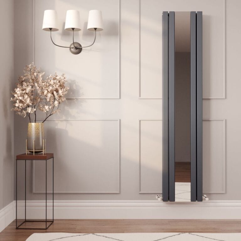 Milano Icon anthracite vertical mirrored designer radiator on cream wall nearby triple light fitting above small table with gold vase and artificial houseplant