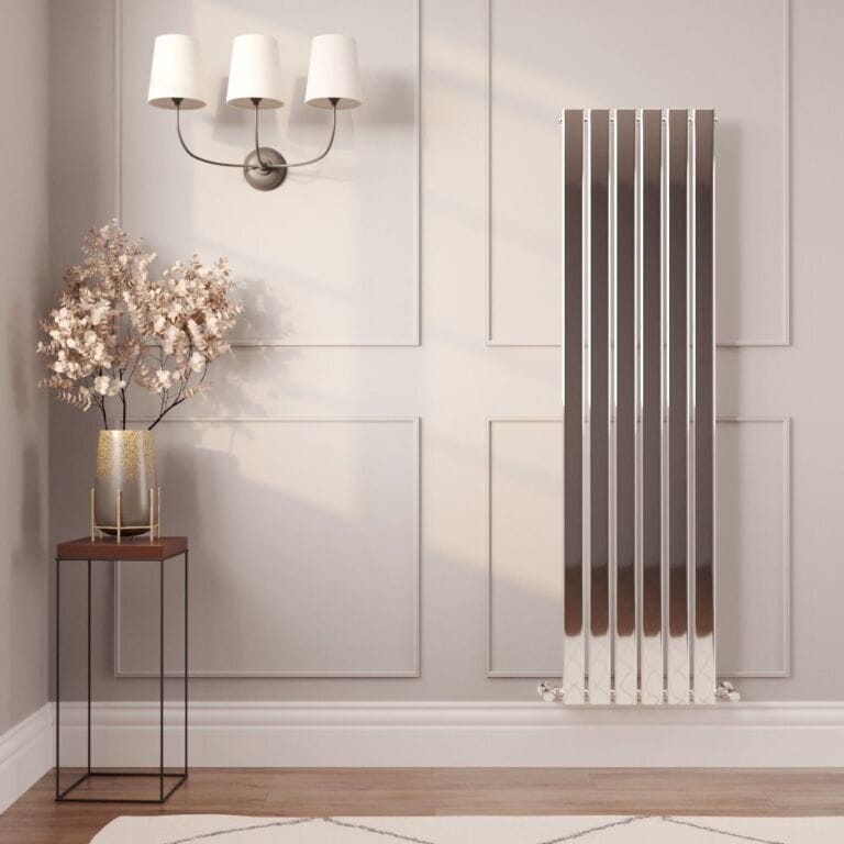 Milano Alpha chrome vertical flat panel designer radiator on cream wall nearby small table with artificial plant and a triple lamp fitting