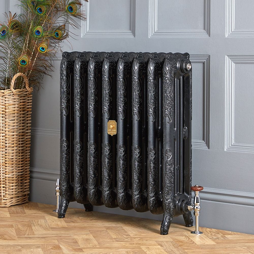 Milano Beatrix black ornate cast iron radiator on light blue background nearby basket with peacock feathers