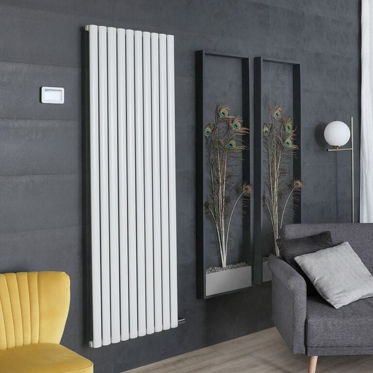 ECOSO Aruba Ardus white dry heat vertical electric designer radiator on dark wall nearby yellow chair and two framed peacock feather artwork pieces and grey settee with light grey cushion