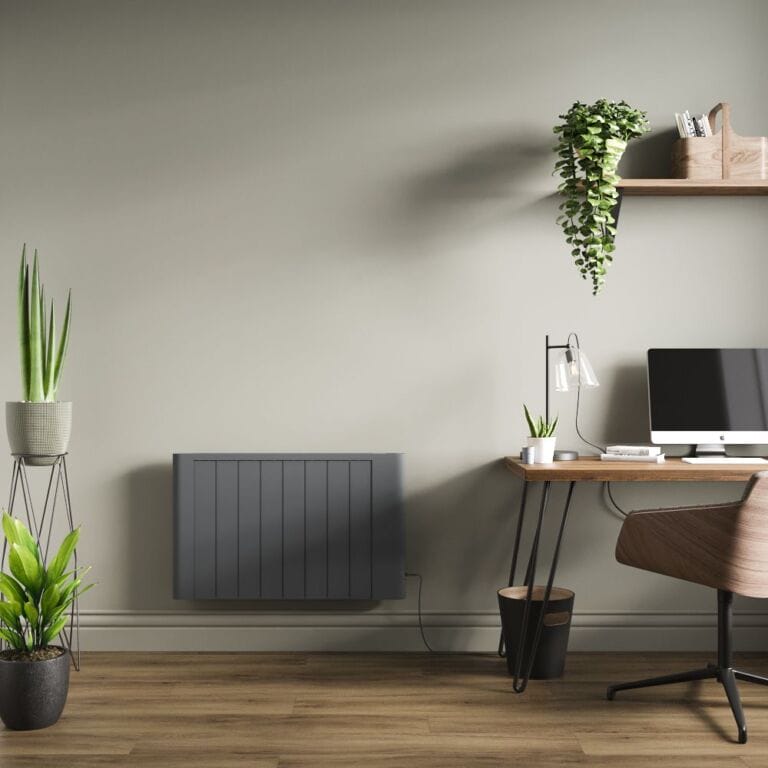Milano Torr anthracite dry heat smart electric plug in heater on light green wall in modern office space nearby computer and shelving with plants