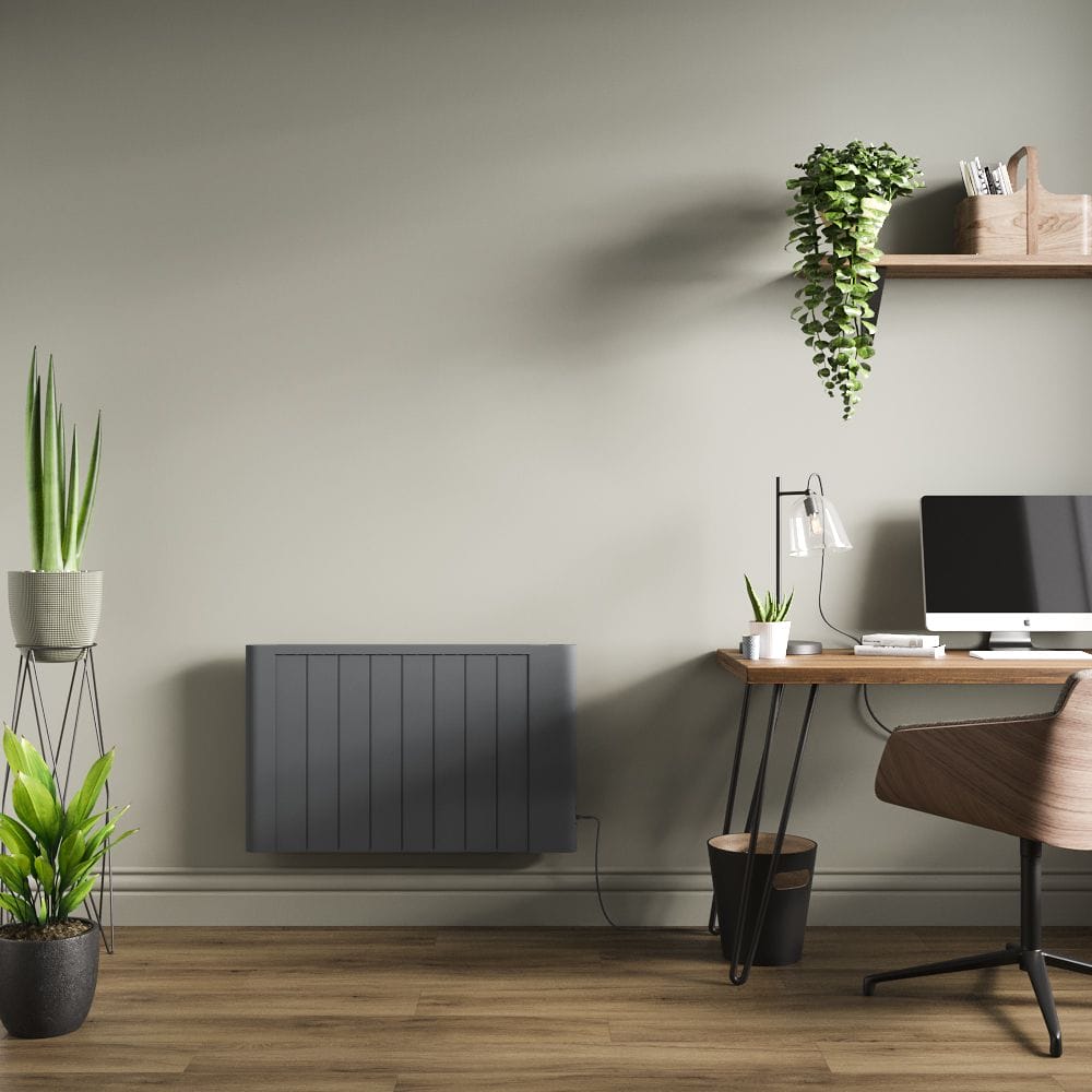 Milano Torr anthracite dry heat smart electric plug in heater on light green wall in modern office space nearby computer and shelving with plants