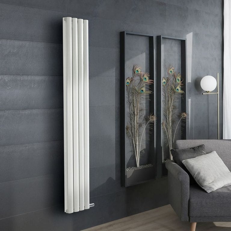 ECOSO Aruba Ardus white dry heat vertical electric designer radiator on anthracite wall nearby framed peacock feathers behind grey settee with cushions