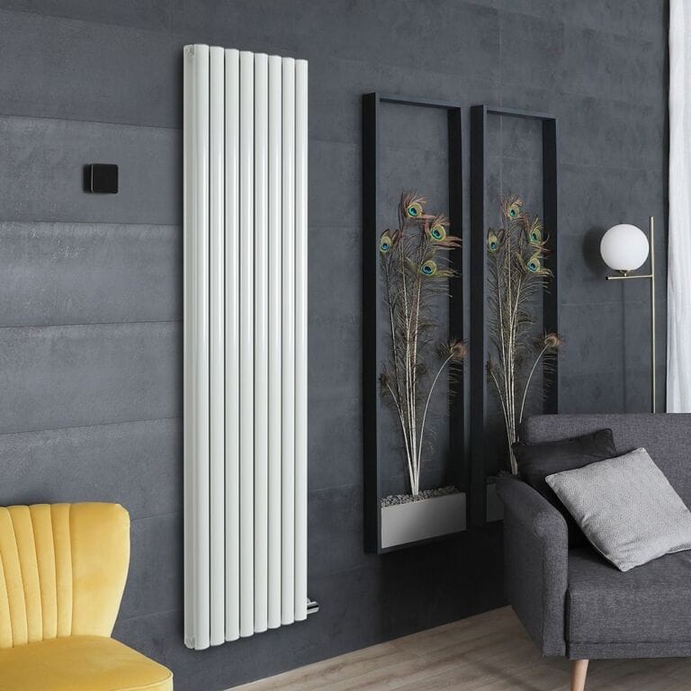 Milano Aruba Ardus white dry heat vertical electric designer radiator on grey wall nearby framed peacock feathers and yellow chair