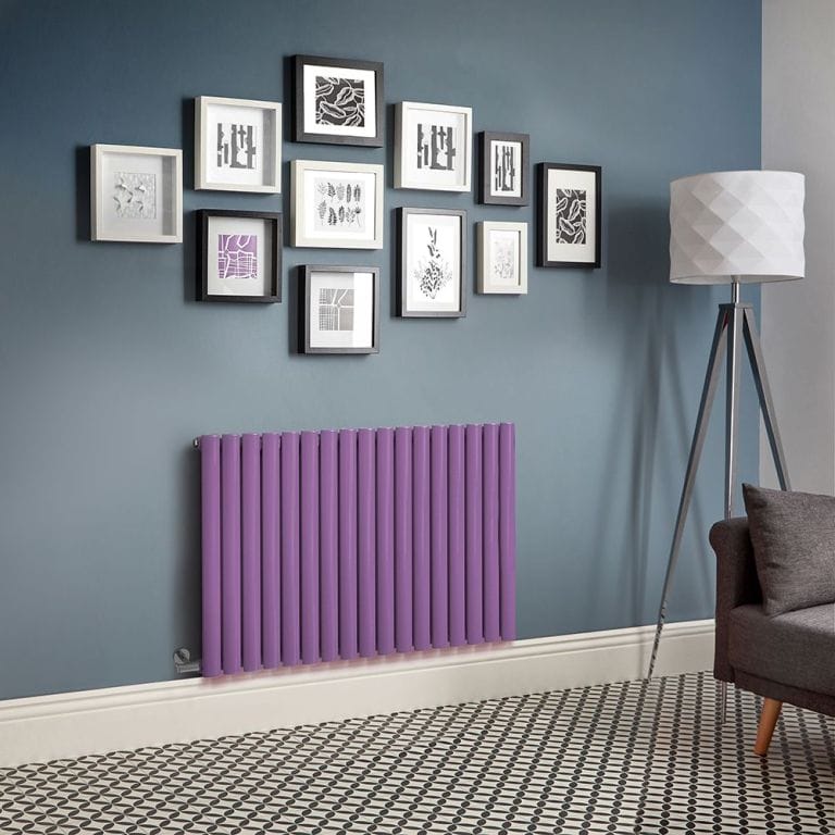 Milano Aruba electric lush purple horizontal designer radiator on blue wall beneath multiple pieces of framed artwork nearby freestanding lamp and dark grey settee