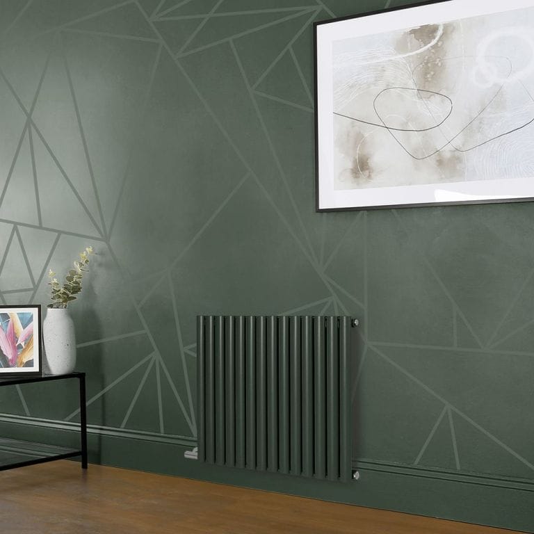 Milano Aruba electric evergreen horizontal designer radiator on green wall beneath large framed art and nearby small black table with vase and framed art