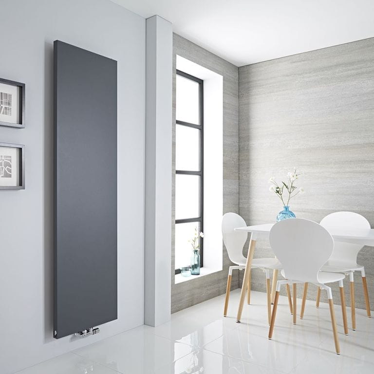 Milano Riso anthracite flat panel vertical designer radiator on white wall nearby vertical window and white plastic table and chairs