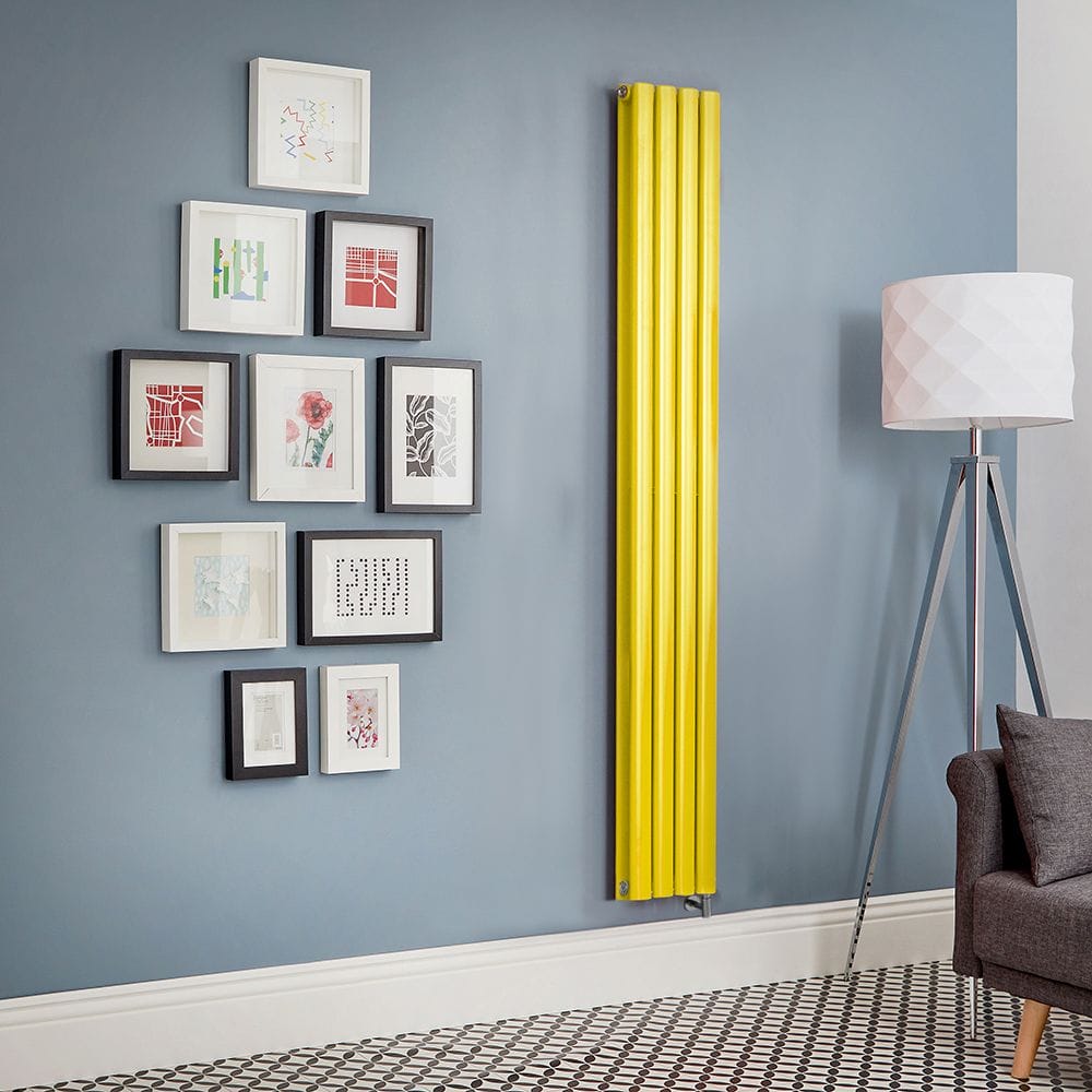 Milano Aruba electric dandelion yellow vertical radiator on light blue wall nearby multiple framed art pictures and freestanding lamp