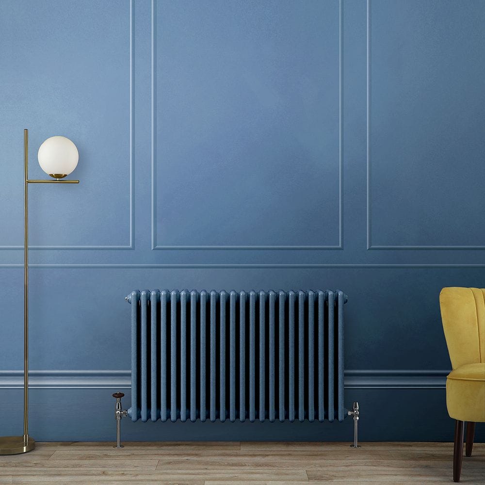 Milano Windsor blue horizontal traditional triple column radiator on blue wall nearby modern freestanding lamp and yellow chair
