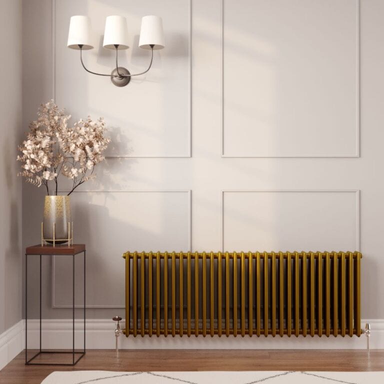 Milano Windsor metallic gold horizontal traditional column radiator on white wall nearby triple light fitting and gold vase on small table