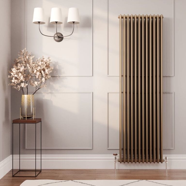 Milano Windsor metallic bronze vertical traditional column radiator on light wall nearby small table with vase and fake houseplant beneath triple light fitting