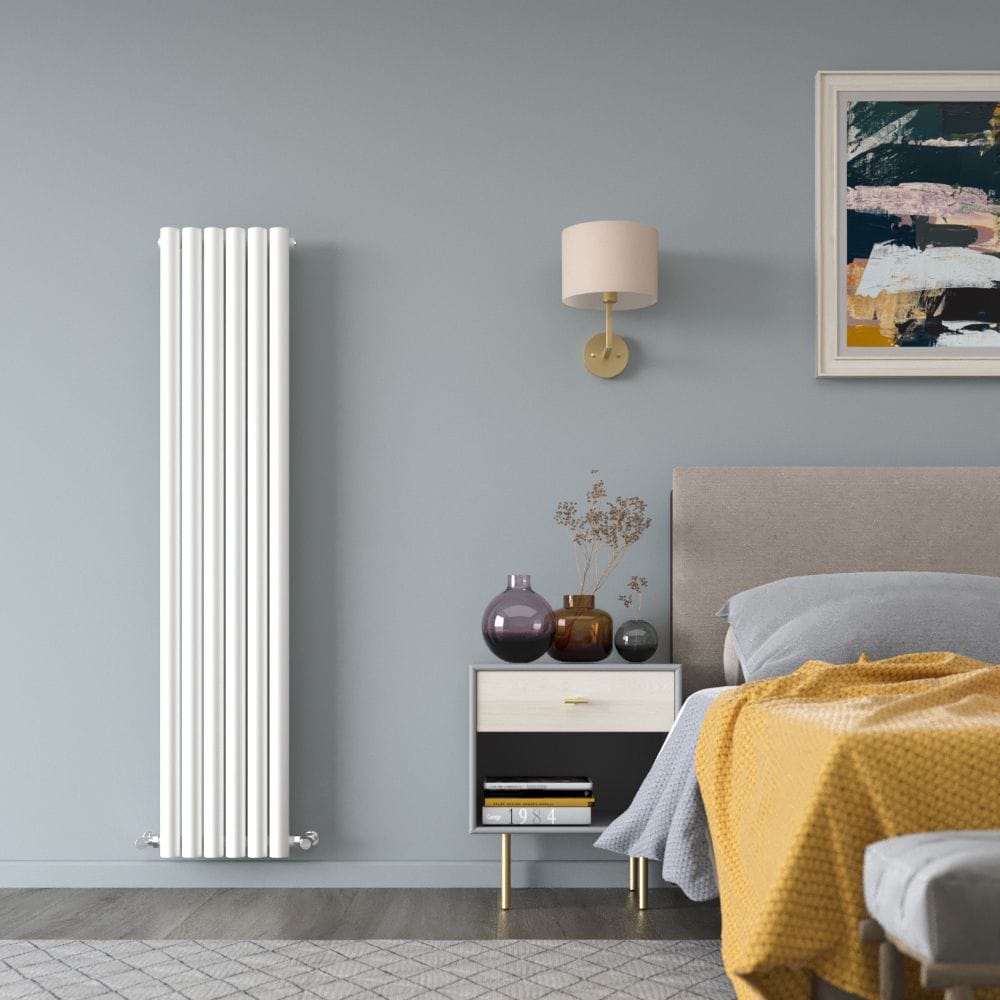 Milano Java white vertical round tube designer radiator on light blue wall in modern bedroom nearby bedside table with multiple vases beneath light fitting and bed beneath artwork