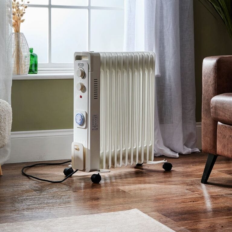 ECOSO Finn white electric portable oil filled radiator on wooden floor in front of window nearby brown leather chair