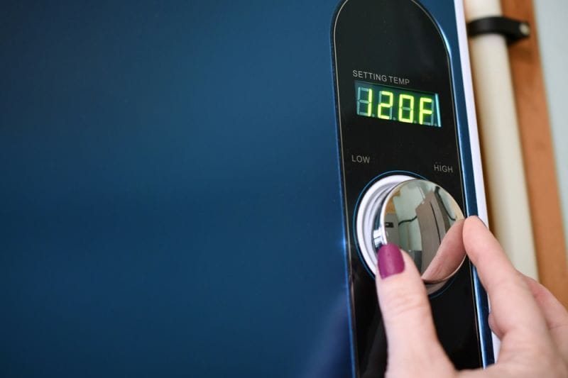 Female hand adjusting dial on a modern blue digital boiler