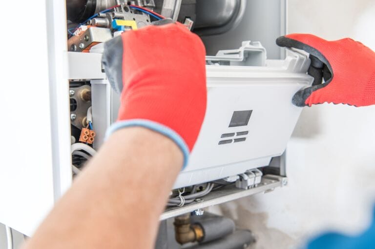 Hands in red gloves attending to gas boiler