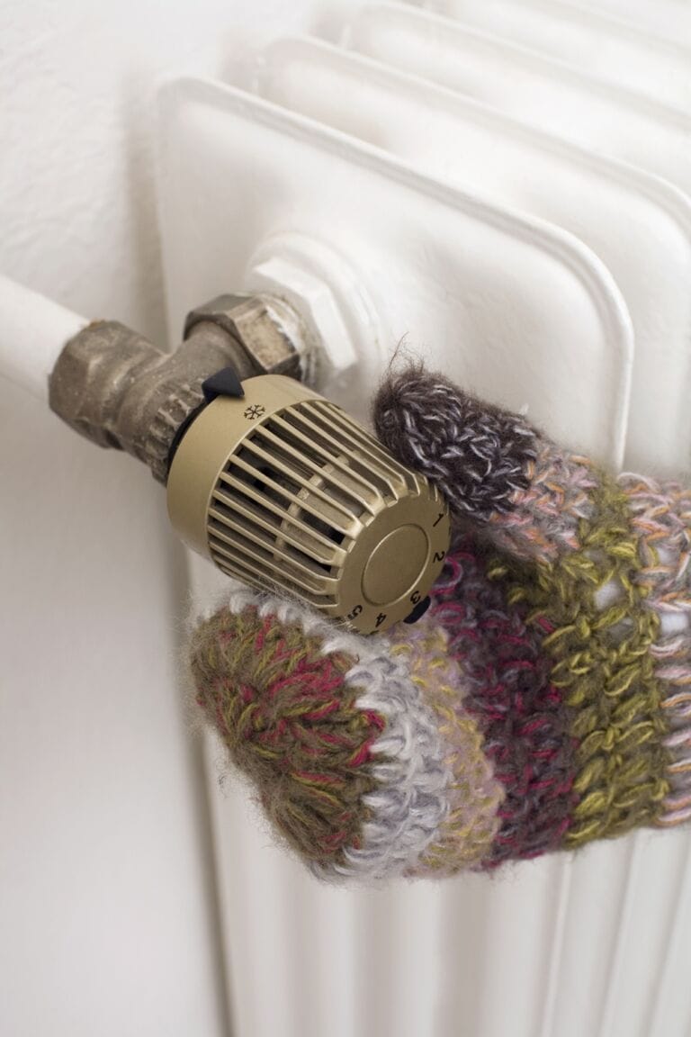 Hand in glove adjusting gold radiator valve on traditional white radiator