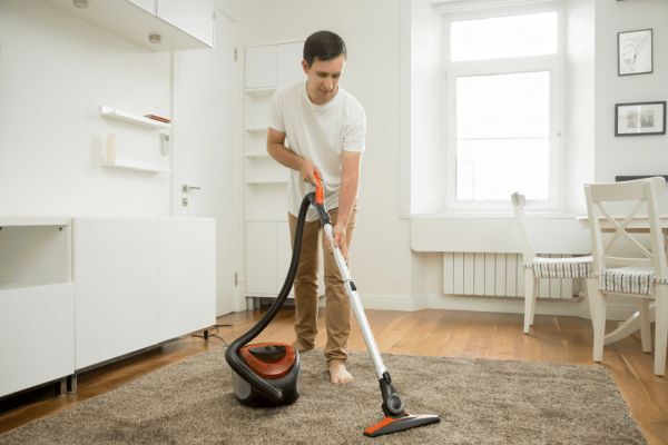 happy man vacuuming the rug
