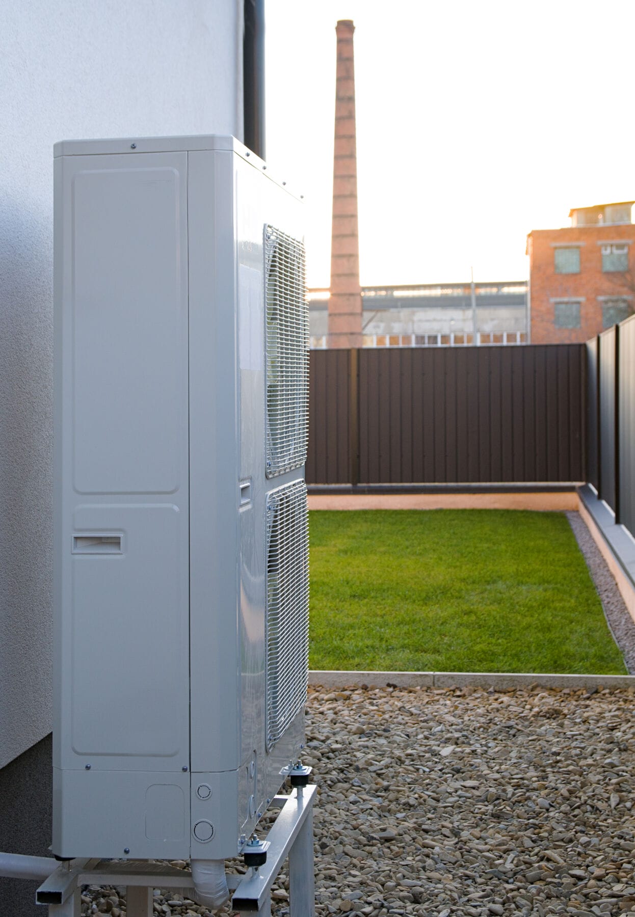 tall grey air source heat pump in modern garden Side-on image of tall grey air source heat pump in modern garden