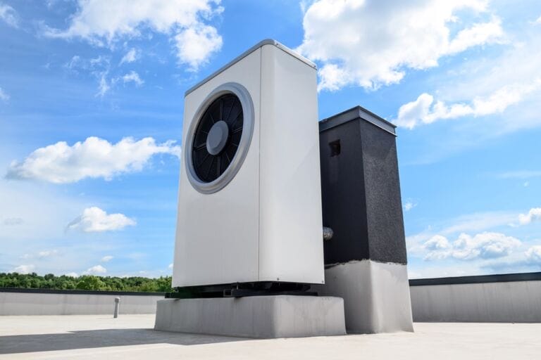 White heat pump system for solar panel link on roof with blue sky and white clouds in background