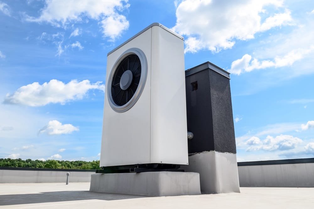 White heat pump system for solar panel link on roof with blue sky and white clouds in background