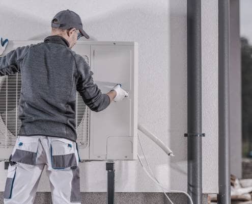 Heating professional with air source heat pump Heating engineer with white gloves tending to air source heat pump