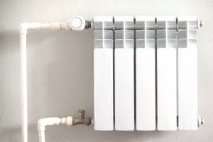 White micro bore pipework feeding into white convector radiator on white wall