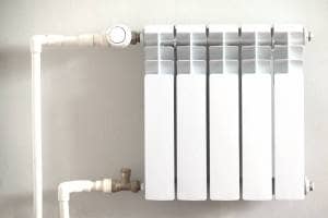 Micro bore pipes and white convector radiator White micro bore pipework feeding into white convector radiator on white wall