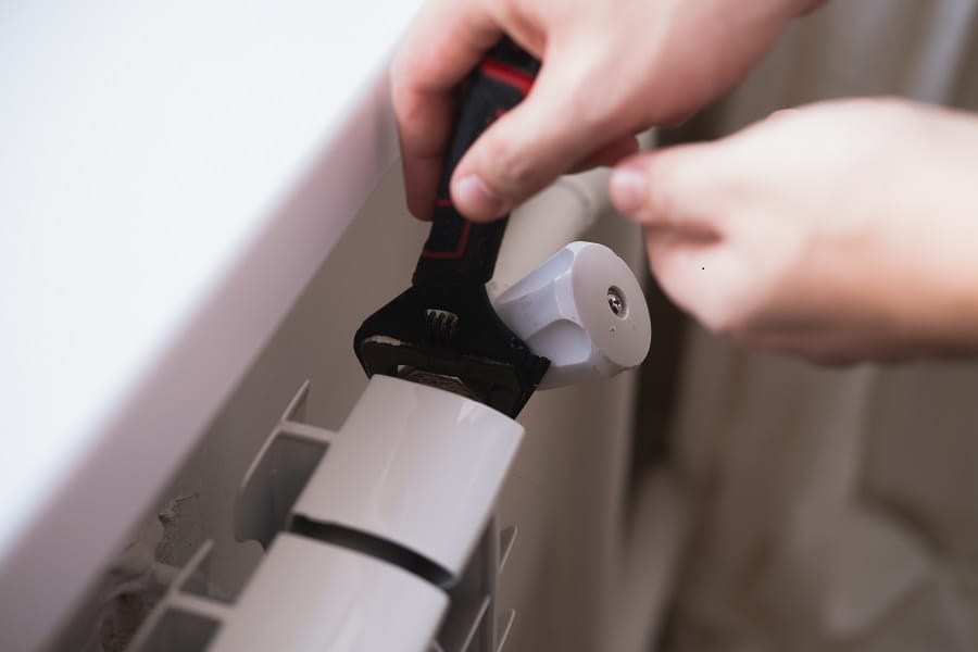 Hand adjusting bleed valve on radiator