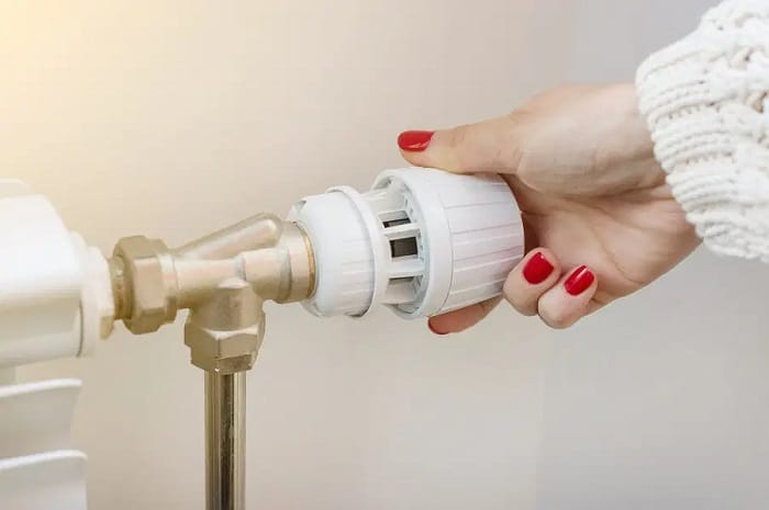 a woman turning a thermostatic radiator valve on a heating appliance a woman turning a thermostatic radiator valve on a heating appliance