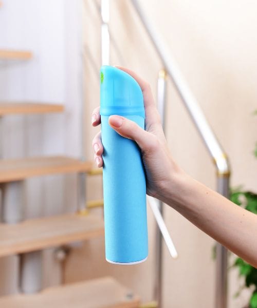 hand holding a can of air freshener home heating hacks to avoid