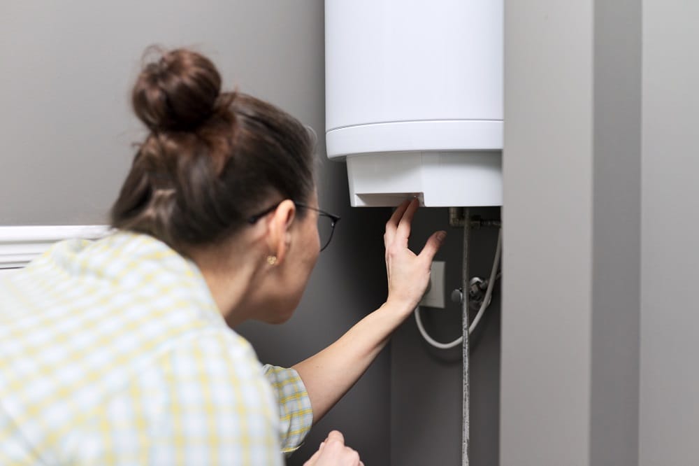 Woman regulating temperature on water heater tank
